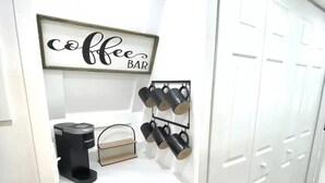 A kitchenette with a coffee bar sign, a coffee maker, and a mug rack. - Kayak Cottage - Free kayaks and fire pit (Lampe)