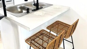 A modern kitchen with a white countertop, a sink, and two wicker bar stools. - Kayak Cottage - Free kayaks and fire pit (Lampe)