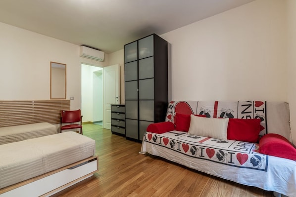 A bedroom with a bed, a sofa, a wardrobe, and a mirror.