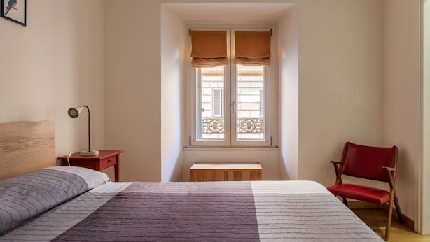 Una camera da letto con un letto, una scrivania, una sedia, una finestra con tende e un quadro appeso al muro.