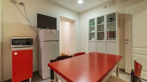 Una cucina compatta con forno a microonde, frigorifero e TV a parete.