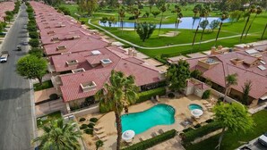 Un quartier résidentiel où les maisons se distinguent par leurs toits recouverts de tuiles rouges, une piscine et, au loin, un terrain de golf.