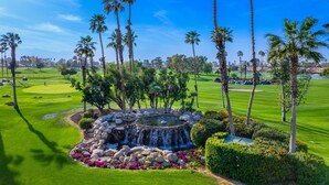 Un parcours de golf doté d’un bassin central, entouré de palmiers et de pelouses parfaitement entretenues.
