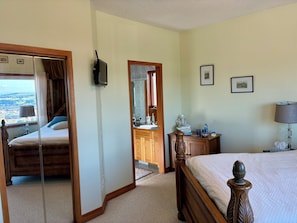 Une chambre d’hôtel avec un lit, une commode en bois, un miroir et une vue sur l’extérieur.