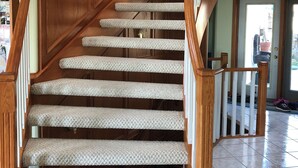 Un escalier en bois avec des marches recouvertes de moquette et une main courante.