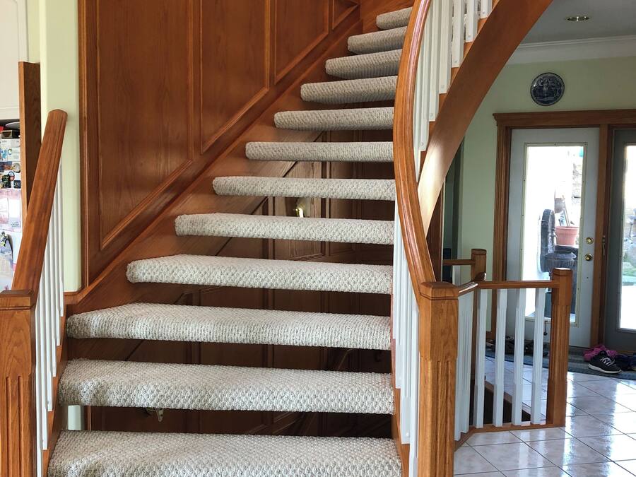 A wooden staircase with carpeted steps and a handrail.