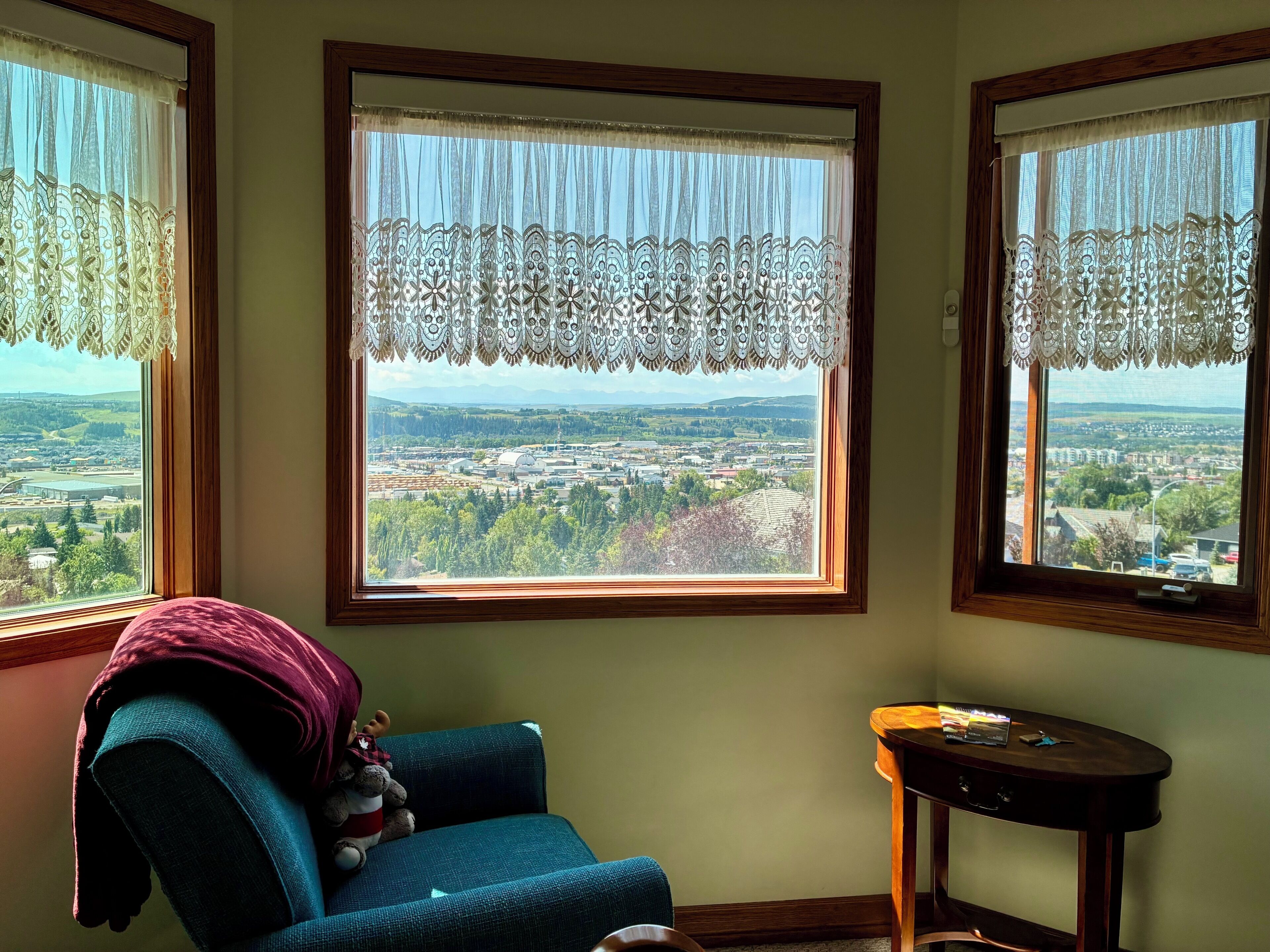 Una habitación con vista a un paisaje urbano a través de una ventana con cortinas de encaje.