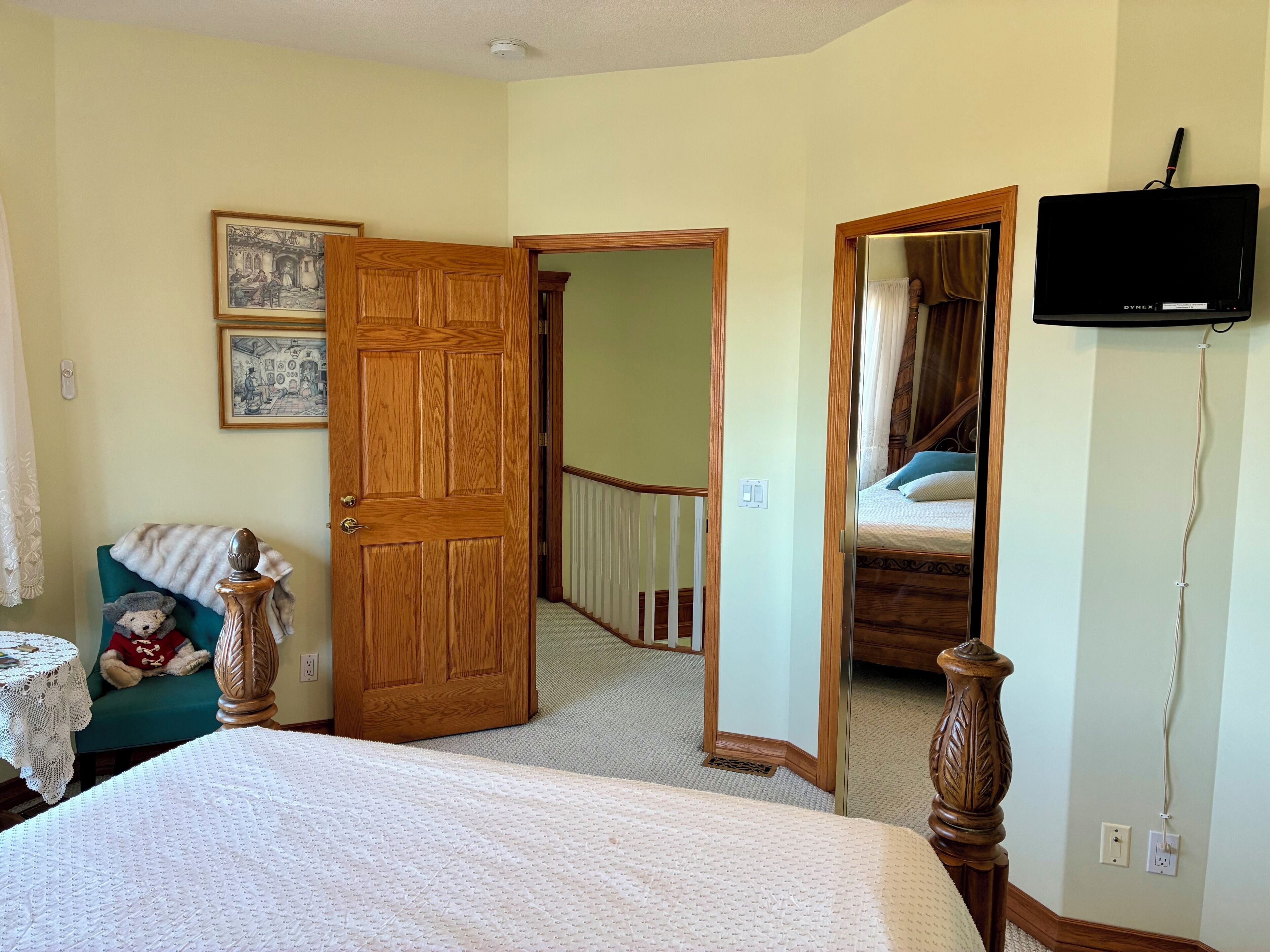 Une chambre à coucher avec un lit, une porte en bois, un miroir, une télévision et un escalier.