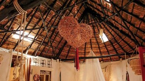 A room with a thatched roof, a bed with a canopy, a hanging heart-shaped decoration, and a rustic aesthetic. - Hotel y Museo Aldea Maya Toktli Orígenes (Izamal)
