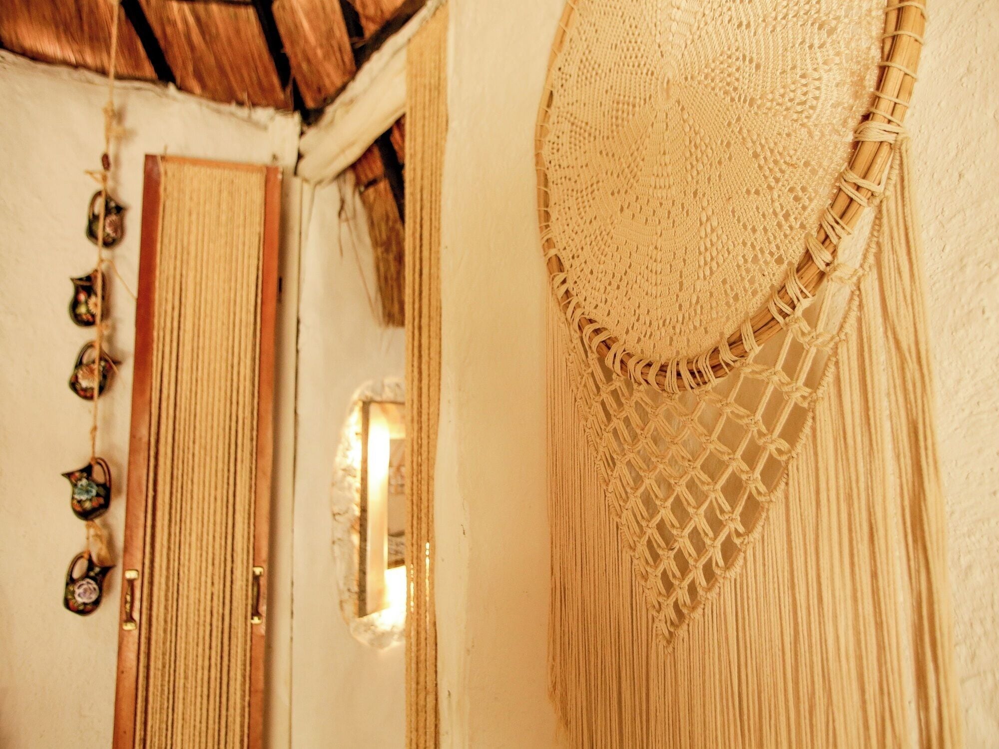 Uma porta com moldura de madeira, um tapete tecido e um painel de macramé na parede.