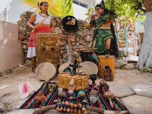 A traditional outdoor setting with stone walls, a palm tree, and various cultural artifacts.