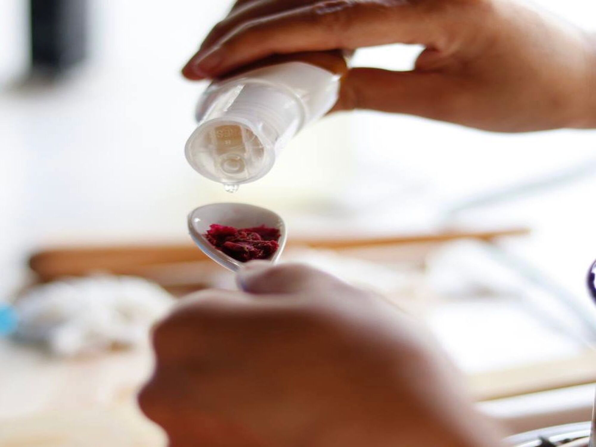 Une personne verse un liquide d’une bouteille dans une cuillère.