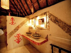 Un baño con un lavamanos de piedra, un espejo y un perchero para toallas.