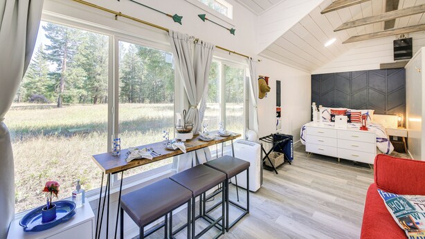 Una habitación moderna con un ventanal grande, una zona de comedor, una cama y un sofá rojo.