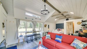 Amplia sala de estar con un sofá rojo, una araña y una mesa de comedor.
