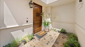 A clean, well-maintained entrance with a wooden door, a potted plant, and a stone-paved area. - Luxury Coastal Home with Rooftop Deck & Ocean Views in Newport Beach (Newport Beach)