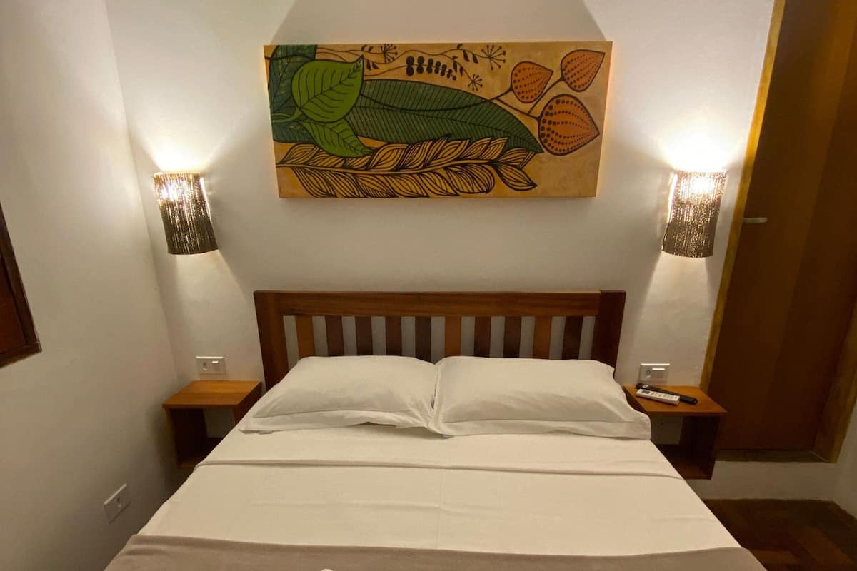 A hotel room with a bed, two bedside tables, and a wall-mounted artwork above the bed.