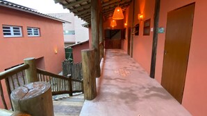 A corridor with a wooden railing, a wooden door, and a patterned floor. - Lalabella Praia Grande (Ubatuba)