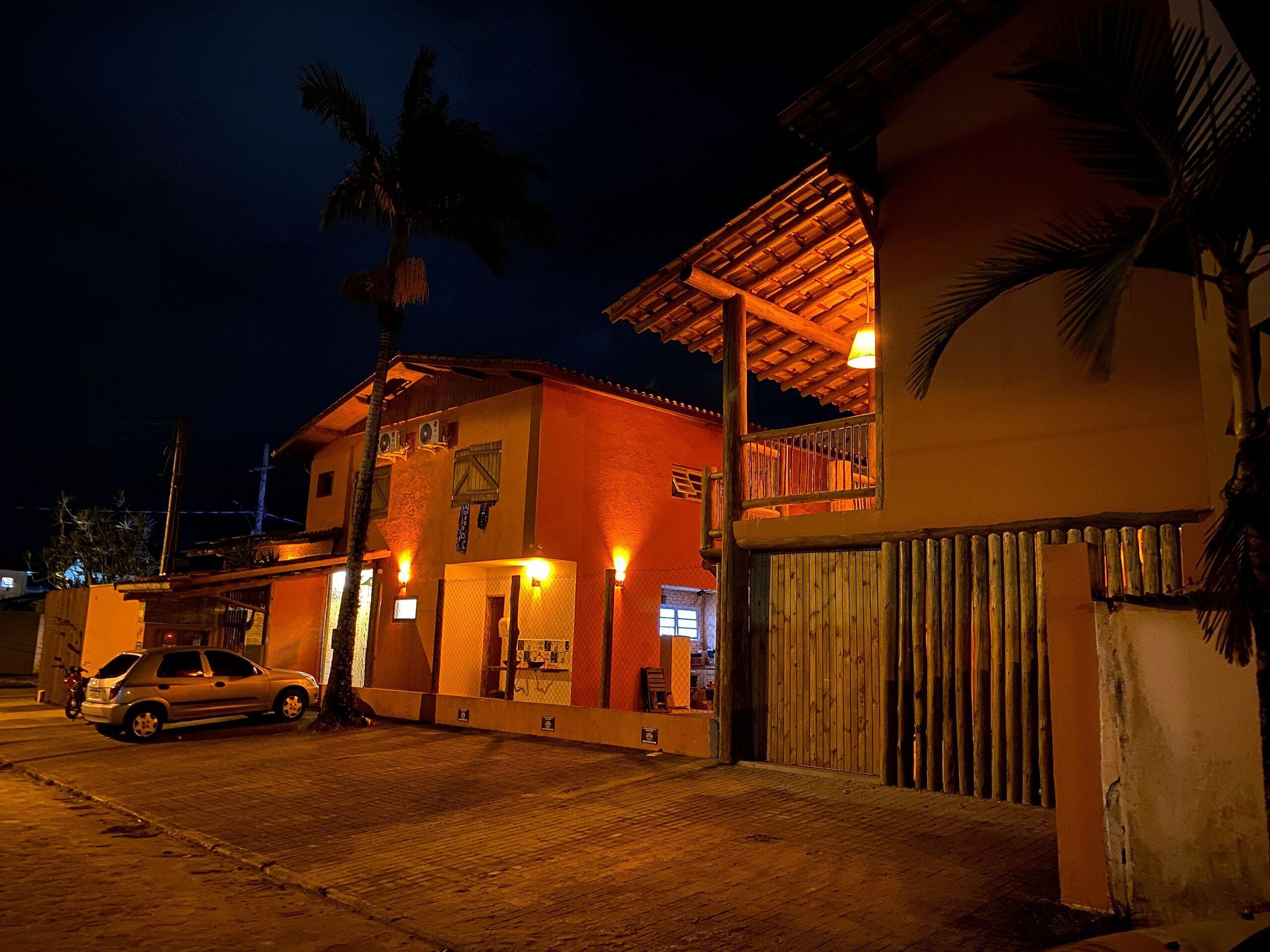 A building with a red facade, a wooden balcony, and a gated entrance.