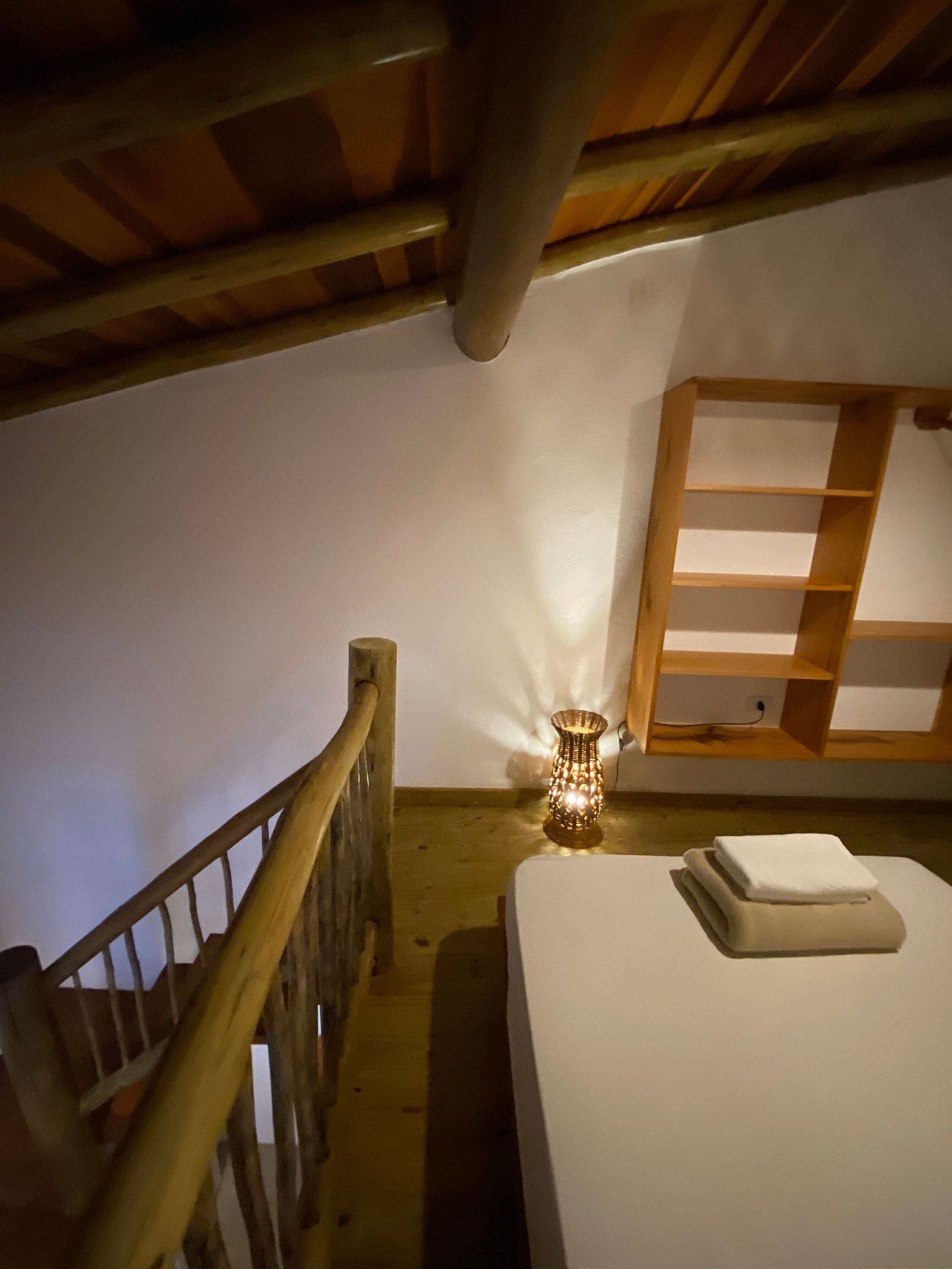 Une chambre avec un lit superposé en bois, une table de chevet avec une lampe et une étagère en bois.