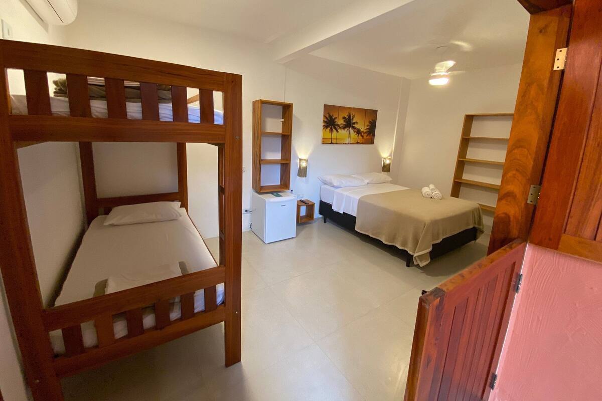 A room with bunk beds, a small desk, a nightstand, and a bed with a headboard.