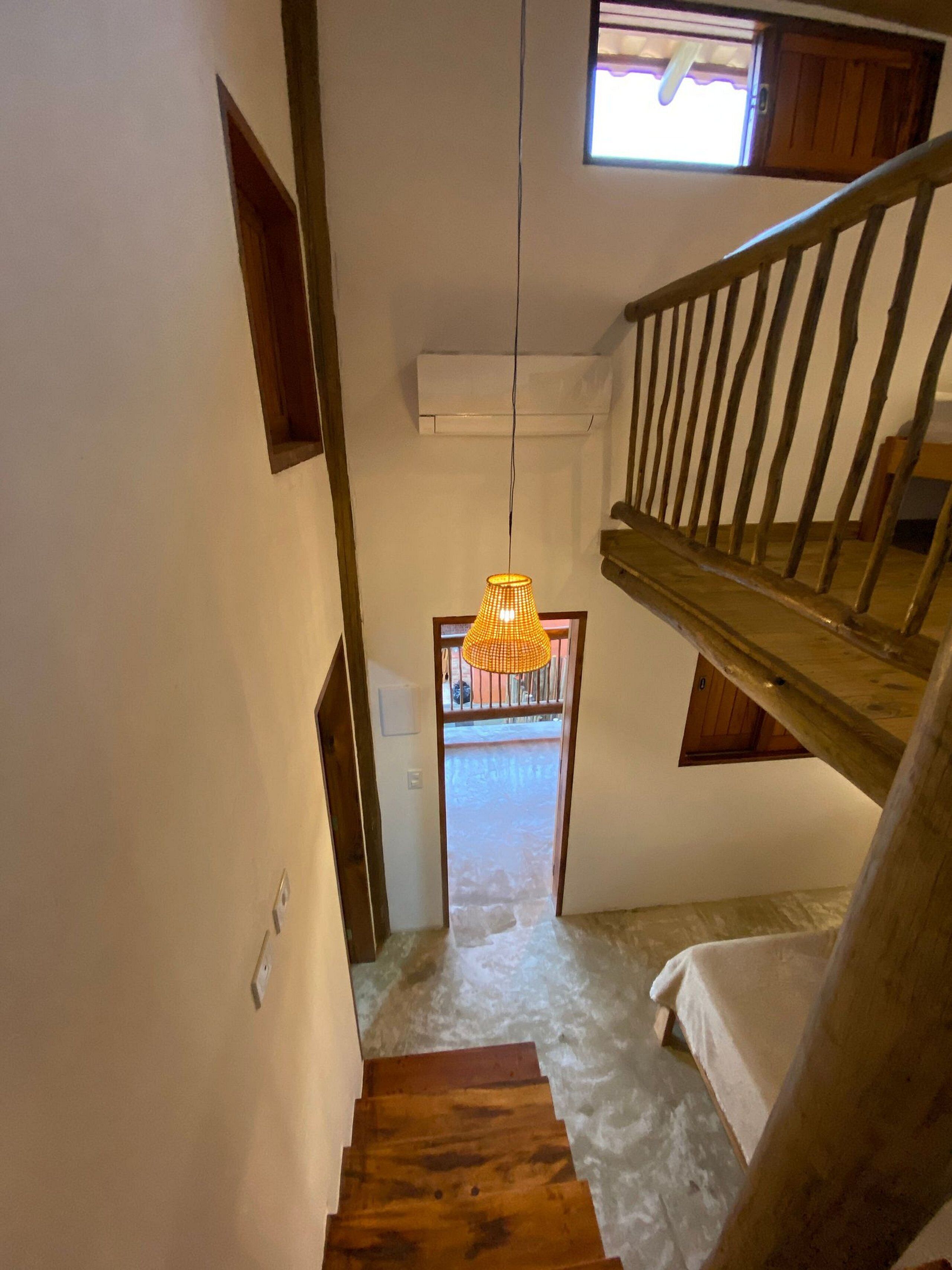 A staircase leading to a balcony with a wooden railing and a hanging light fixture.