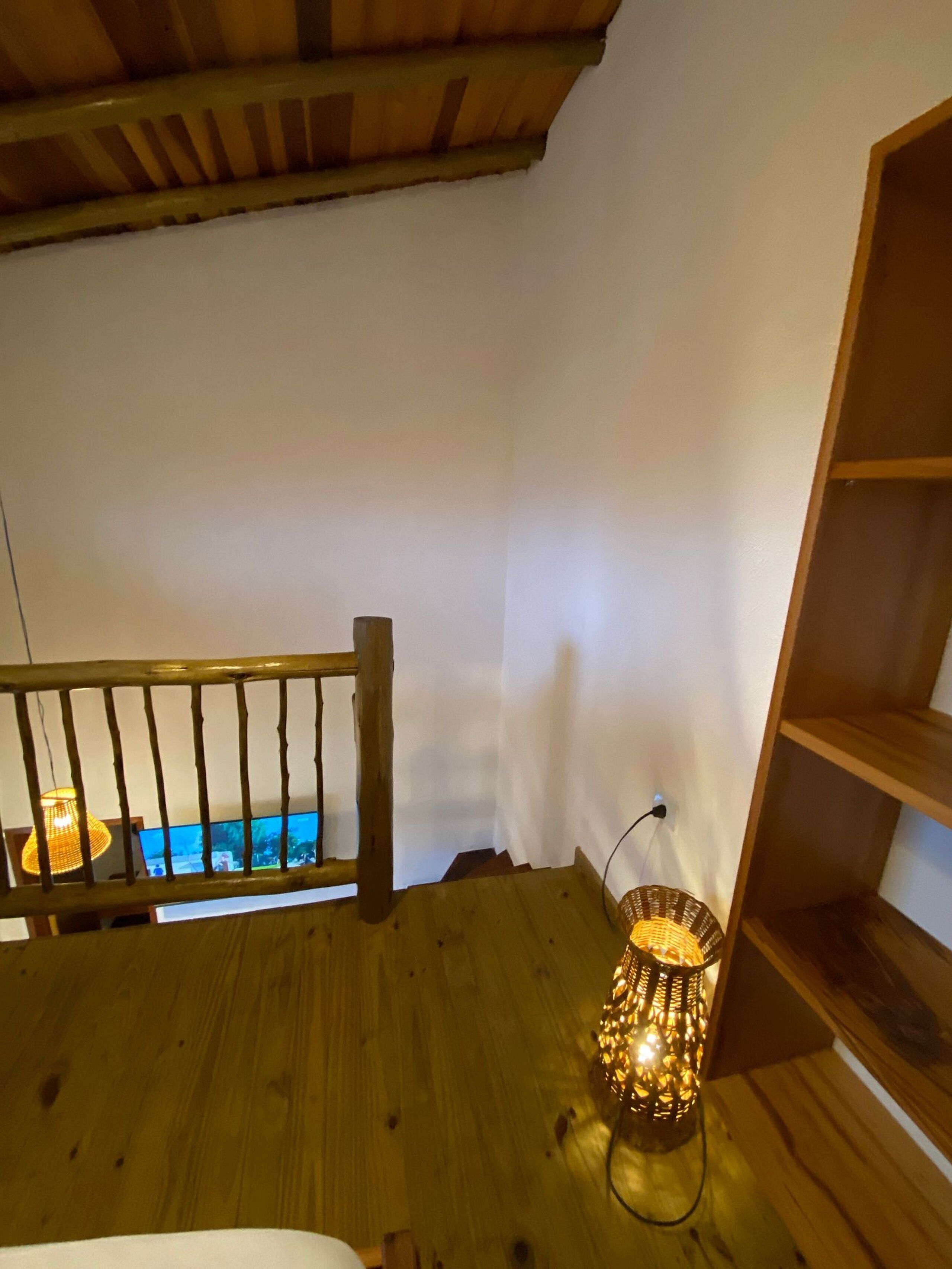 A wooden staircase with a woven lamp on the landing.
