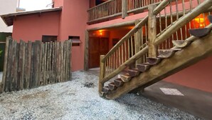 A two-story building with a wooden staircase and a balcony. - Lalabella Praia Grande (Ubatuba)