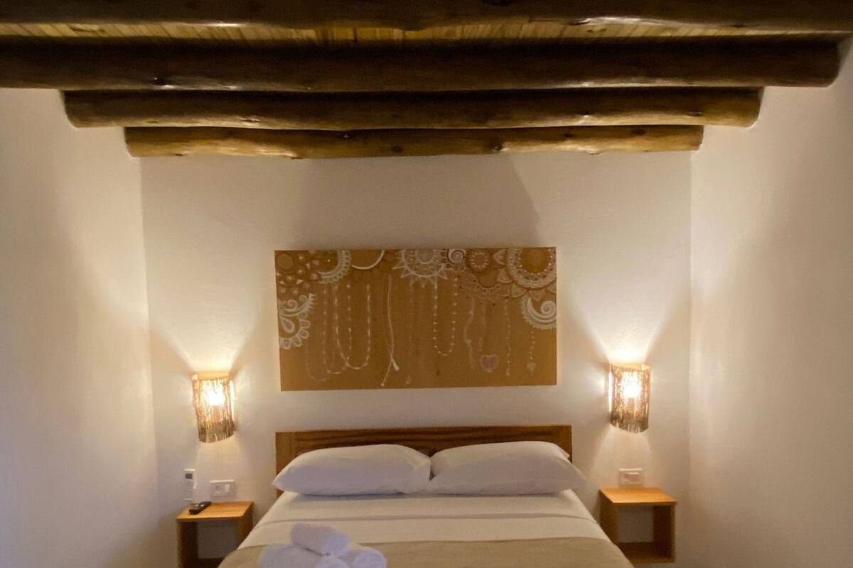 A single bed with a headboard, two bedside lamps, and a wall-mounted artwork.