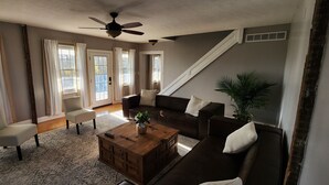 Un salon comprenant un canapé, un fauteuil, une table basse et un ventilateur de plafond.