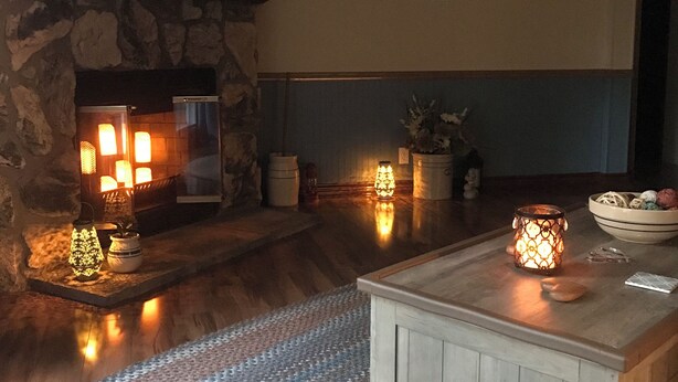 Ein gemütliches Wohnzimmer mit Kamin aus Stein, einem flachbildfernseher darüber und einer bequemen Sitzecke mit einem gemusterten Teppich.