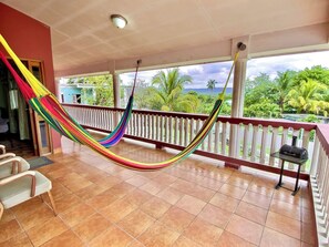 A hammock on a balcony with a view of greenery and a body of water. - Mountain View In Town With King Suite (Midterm Available) (San Ignacio)