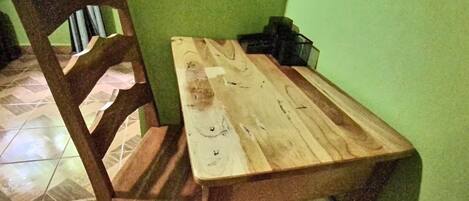 A wooden dining table with a chair, a green wall, and a tiled floor.