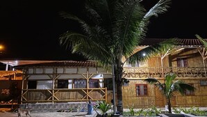 A traditional building with a thatched roof, surrounded by palm trees and a small pool. - Hosteria de Kade (Manglaralto)