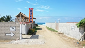 A pathway leading to a building with a sign reading "HOSTERIA MI FANTASIA" and a signpost indicating "HOSTERIA MI FANTASIA" to the left. - Hosteria de Kade (Manglaralto)