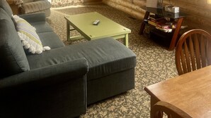 A log cabin interior with a sofa, armchair, and a small table. - Brevort Log Cabin, Michigan's UP (Moran)