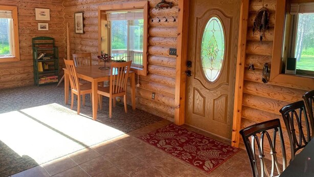 A log cabin interior with a dining area, a door with a stained glass window, and a bookshelf. - Brevort Log Cabin, Michigan's UP (Moran)