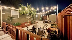 A patio area with outdoor seating, a wooden fence, and string lights.