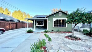 A single-story house with a green exterior, a covered porch, and a stone patio.
