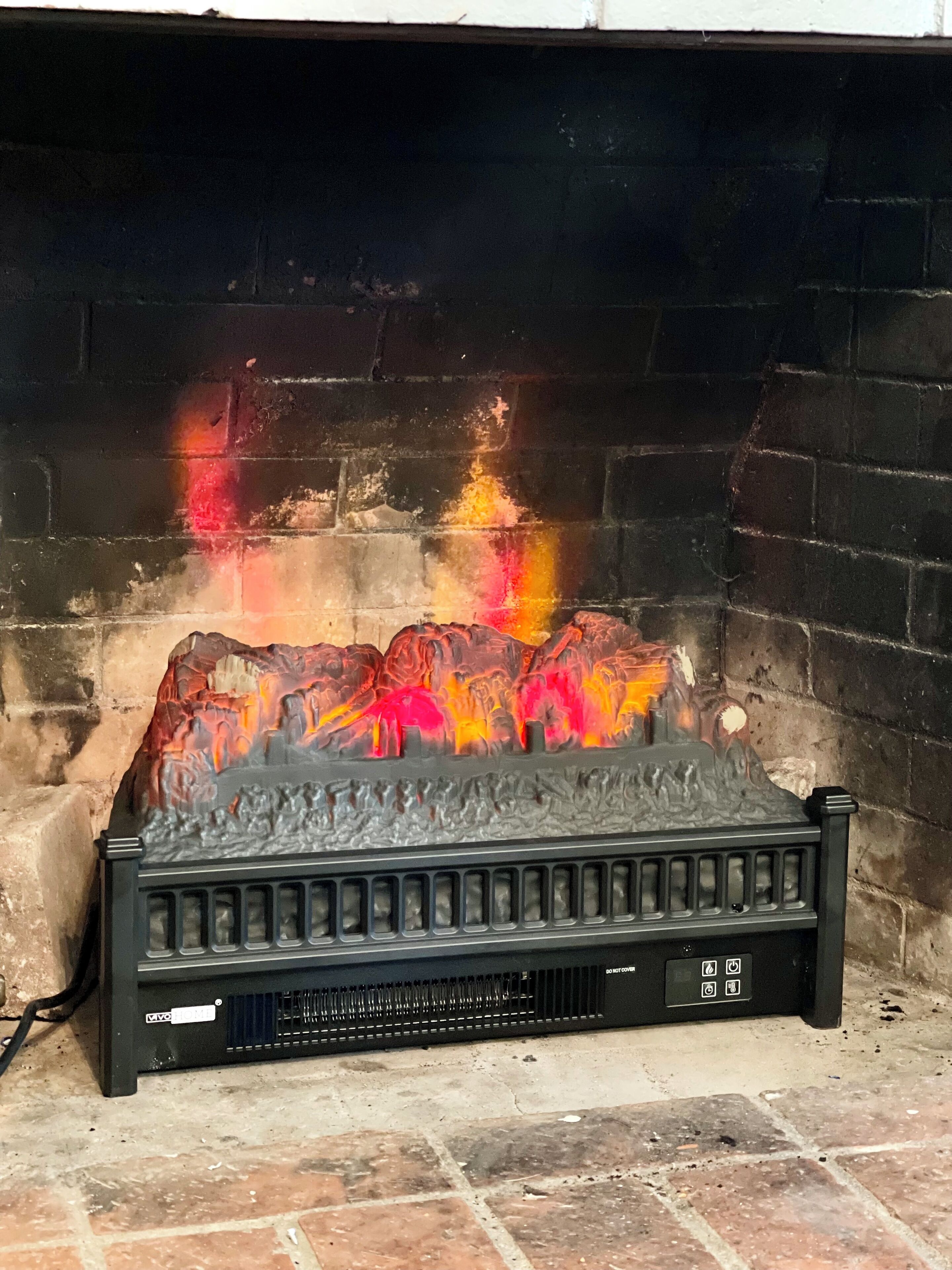 Ein Kamin mit brennendem Feuer, umgeben von einer Ziegelwand.