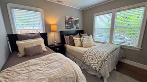 A bedroom with two beds, a nightstand, a lamp, and a picture on the wall.
