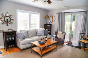 A living room with a sofa, a coffee table, a bookshelf, and a dining area with a chair.