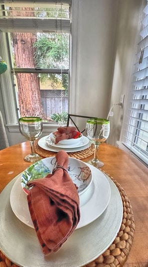A dining table with two plates, each with a glass of wine, set on a woven placemat. - The Downtown Napa Getaway (Napa)
