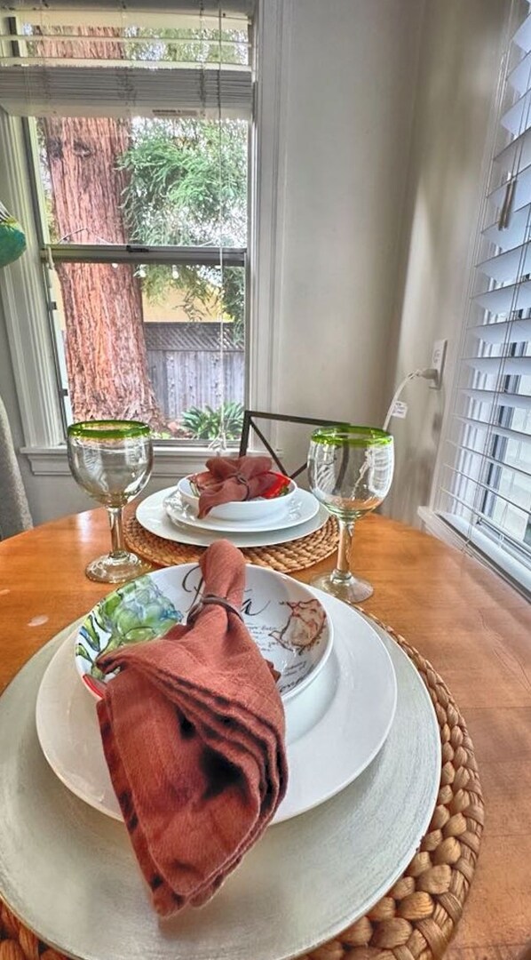 A dining table with two plates, each with a glass of wine, set on a woven placemat.