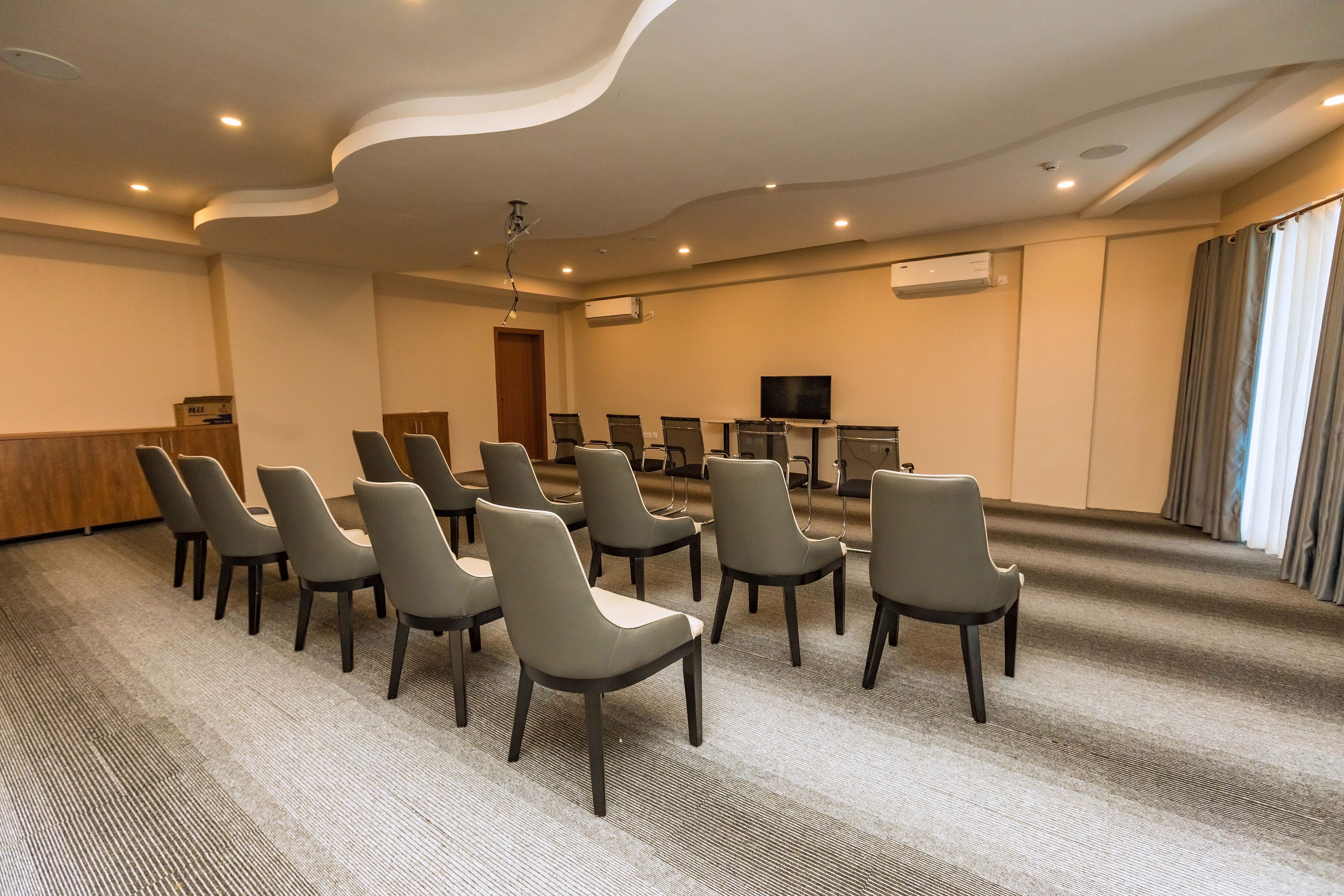 A conference room with a long table and chairs, an air conditioning unit, and a television on the wall.