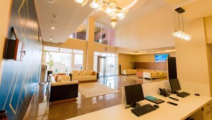 A modern hotel lobby with a reception desk, seating area, and large windows. - The Hut Restaurant & Boutique hotel (Kigali)