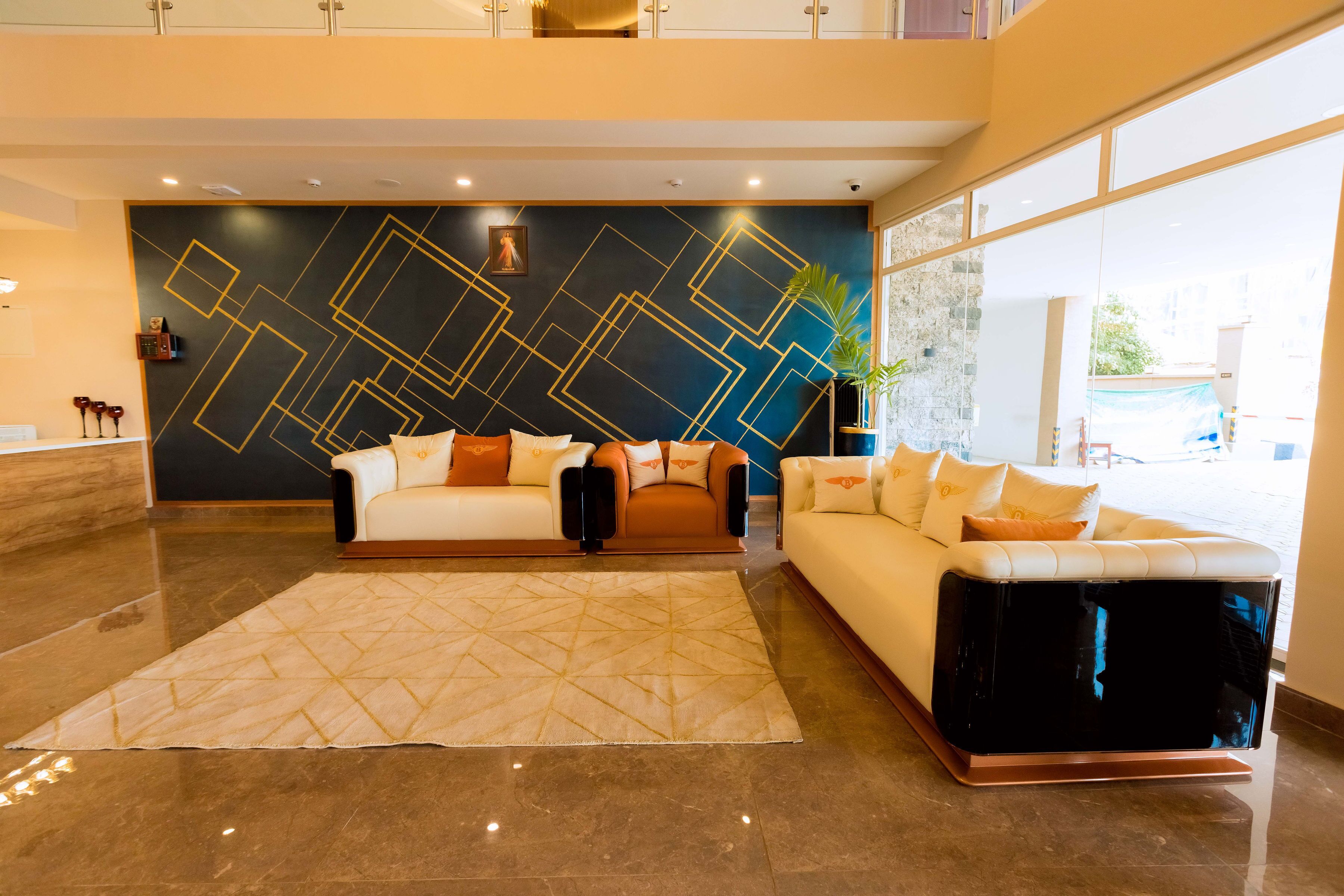 Een moderne lobby met twee banken, een groot vloerkleed en een geometrisch wandontwerp.