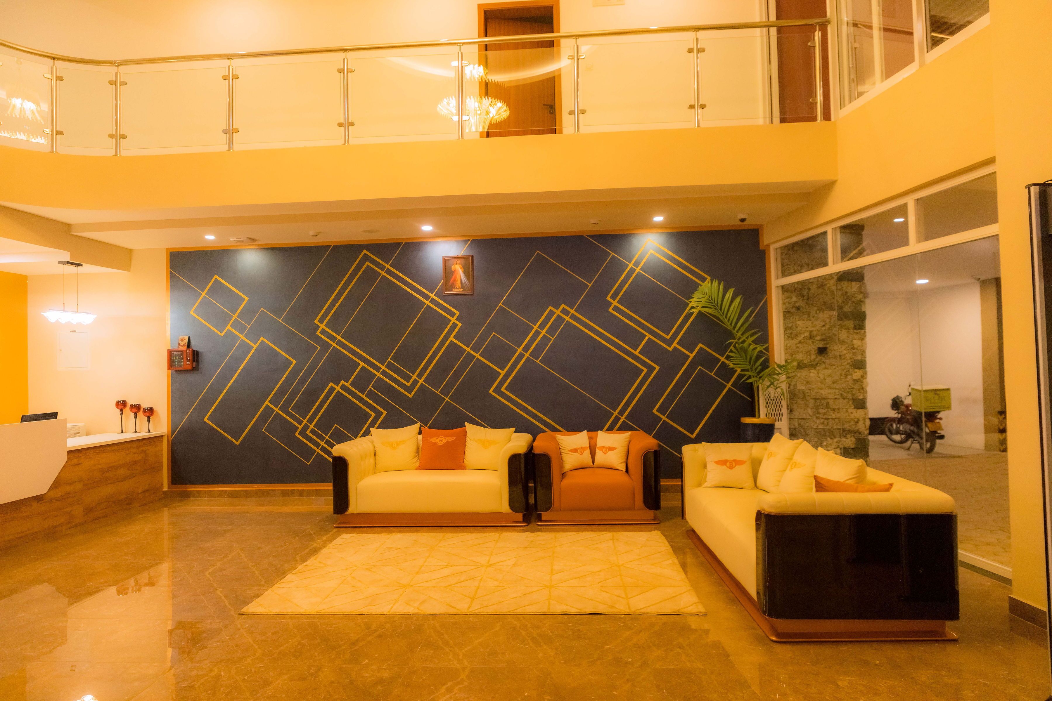 A spacious lobby with a high ceiling, a double-height balcony, and a modern geometric wall design.
