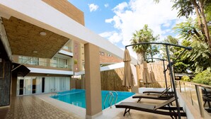 A pool area with a wooden deck, lounge chairs, and umbrellas. - The Hut Restaurant & Boutique hotel (Kigali)