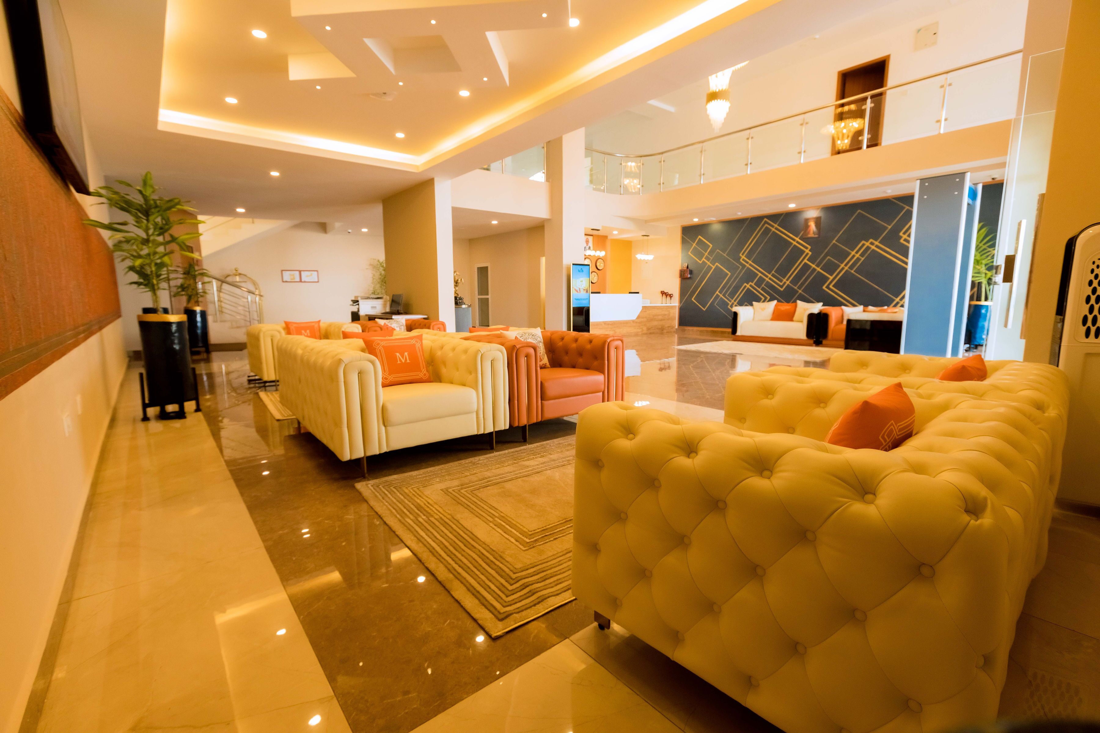 A spacious lobby with a high ceiling, a reception desk, and a seating area with sofas and armchairs.